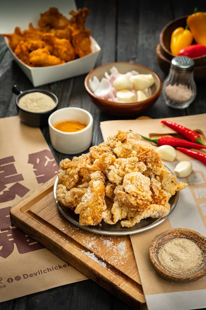 Fried chicken pieces, spices, and ingredients arranged on a dark wooden surface.