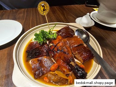 A dish of roasted duck with sauce and garnishes on a wooden table.