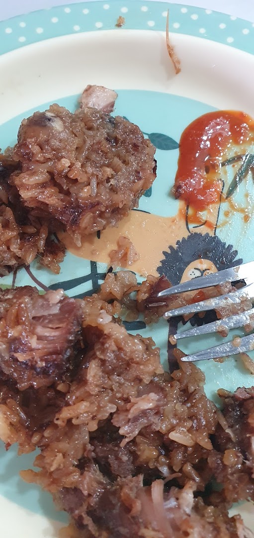 Close-up of sticky rice and meat on a plate with a fork and sauce.