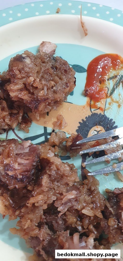 Close-up of sticky rice and meat on a plate with a fork and sauce.