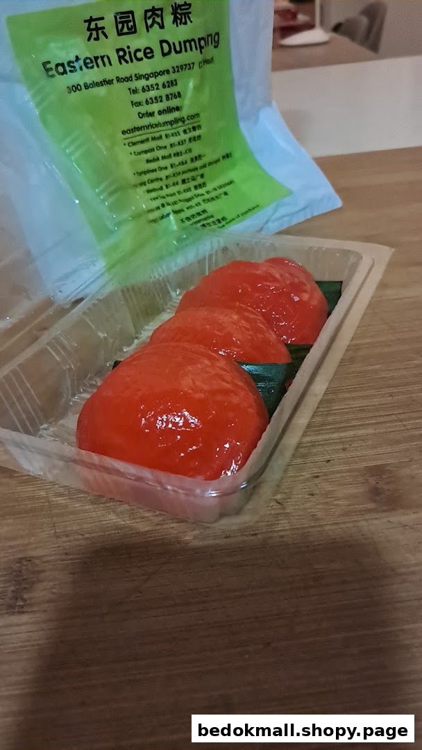 Three red kueh in a plastic container with shop packaging.