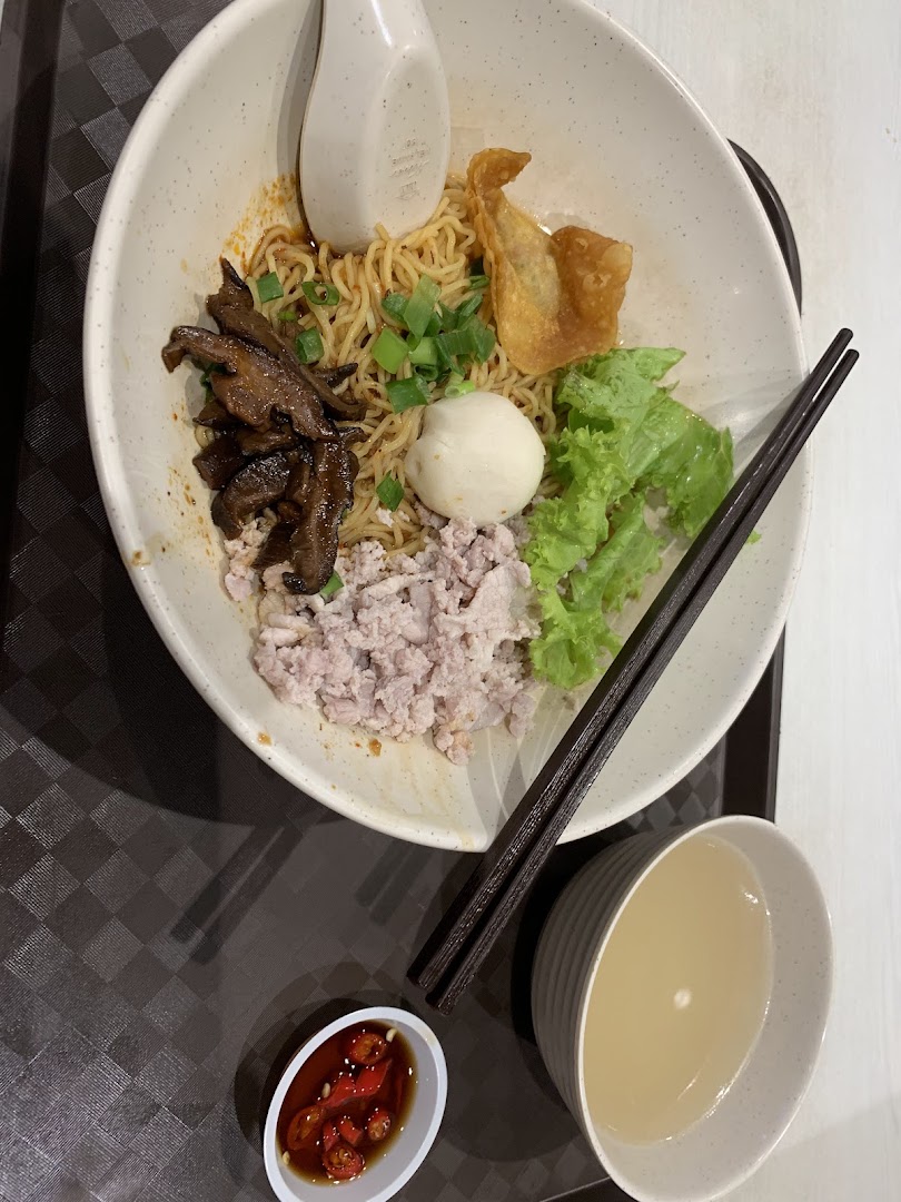 A bowl of noodles with various toppings, chopsticks, and a side of soup.