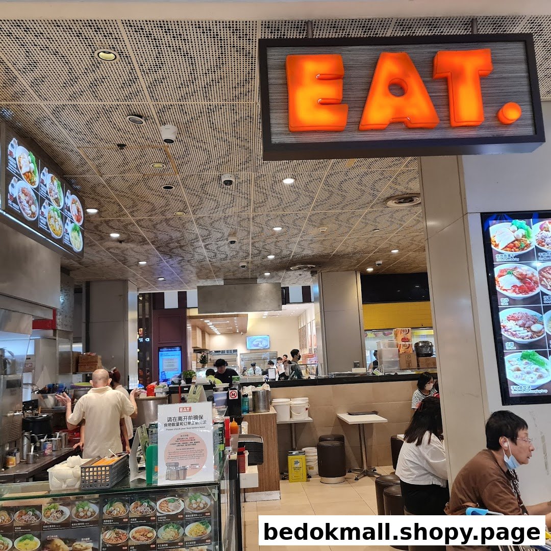A busy food stall interior with staff, customers, and food displays.
