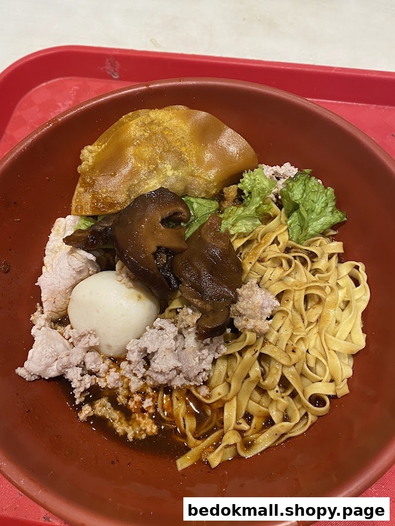 A bowl of noodles with minced meat, mushrooms, and a fried dumpling.