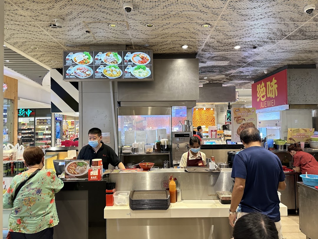 Busy food stall with staff serving customers and a menu display.