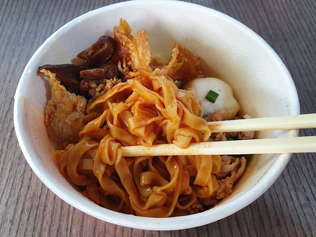 A close-up of a bowl of noodles with various toppings and chopsticks.