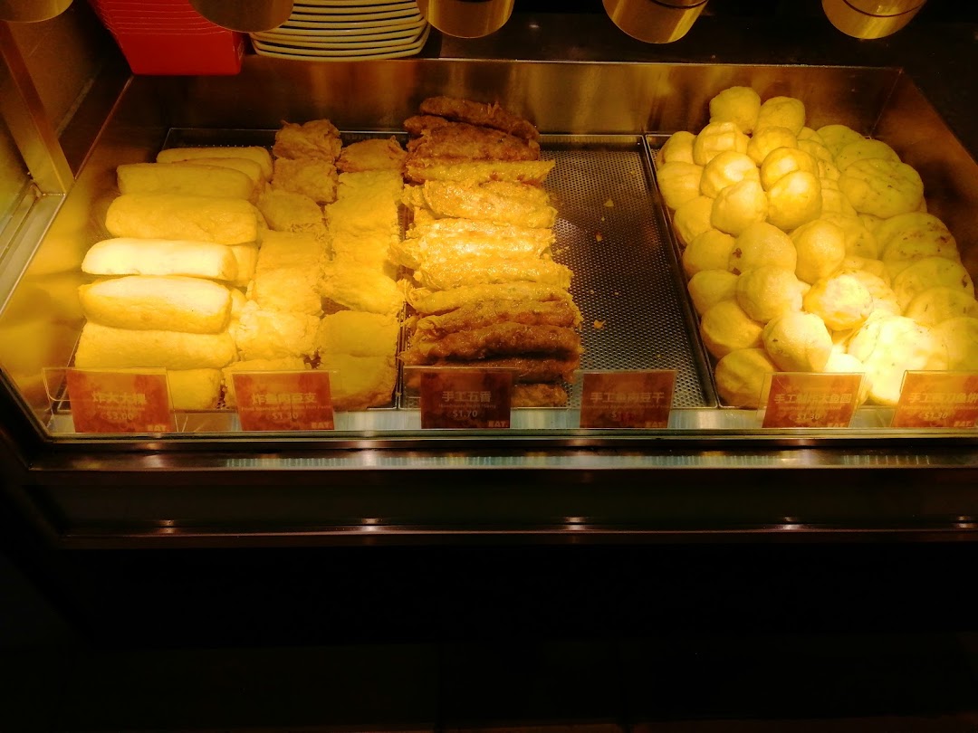 A display case filled with various fried food items and price tags.