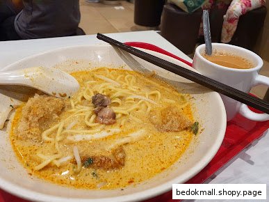 Close-up of a bowl of curry noodles and a cup of coffee.