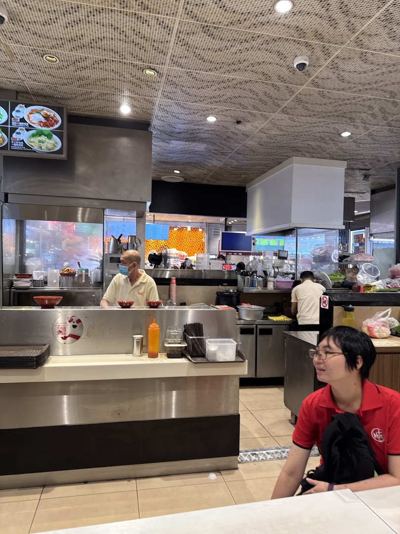 Interior view of a food stall with staff behind the counter and a customer.