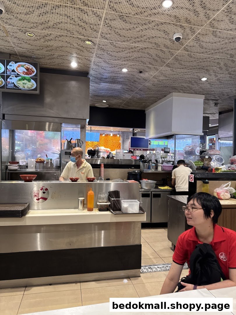 Interior view of a food stall with staff behind the counter and a customer.