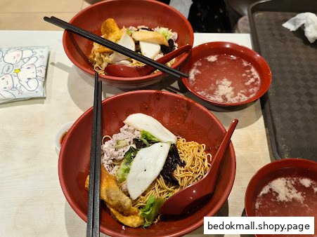 Two bowls of noodles with toppings and soup on a table.