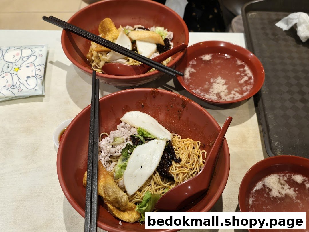 Two bowls of noodles with toppings and soup on a table.