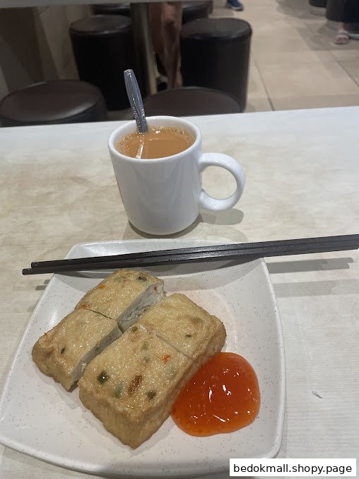 Plate of fried food with sauce, chopsticks, and a mug of tea on a table.