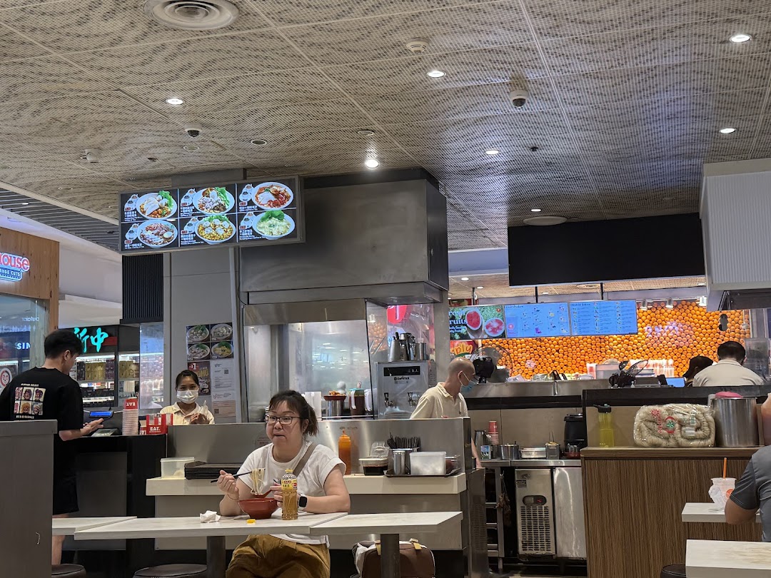 Interior view of a food court with customers eating and staff working.