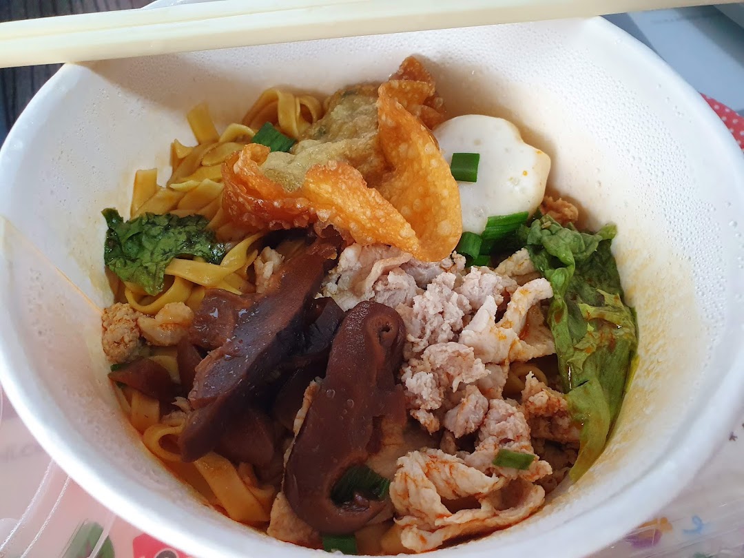 A close-up of a bowl of noodles with various toppings and chopsticks.