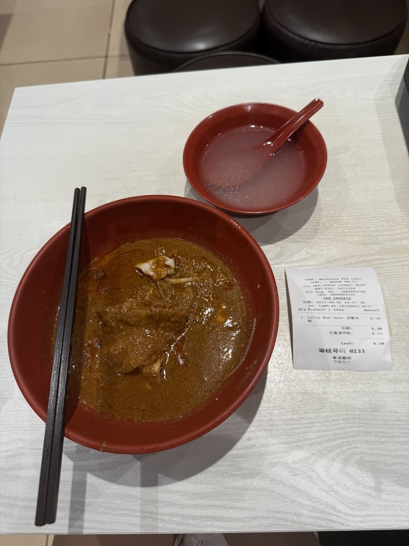 A bowl of noodles, a drink, and a receipt on a table.