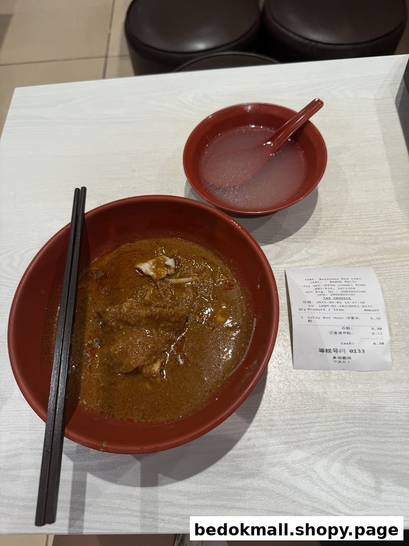 A bowl of noodles, a drink, and a receipt on a table.