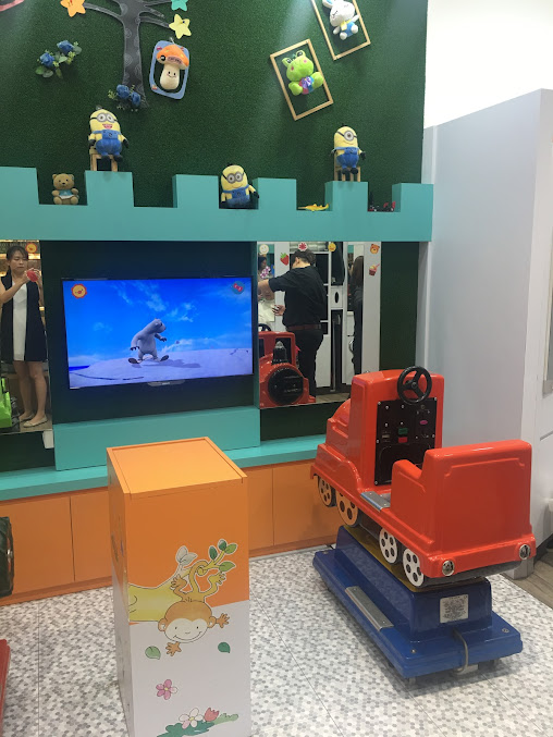 Interior of a children's salon with a TV, train chair, and decorated wall.