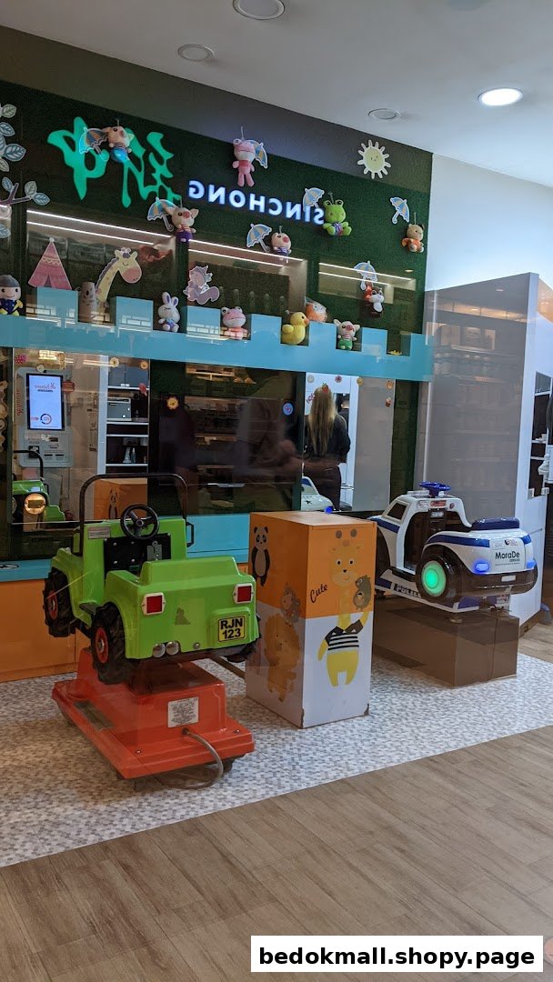Interior view of a shop with two kiddie rides and a decorated wall.