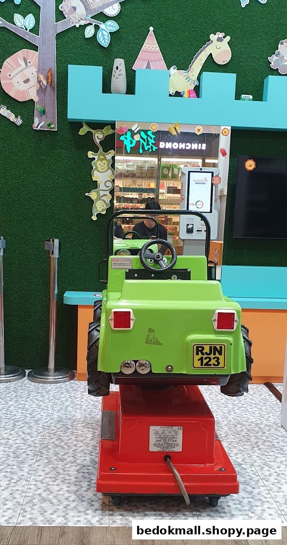 Green ride-on toy in a shop with cartoon animal decorations.