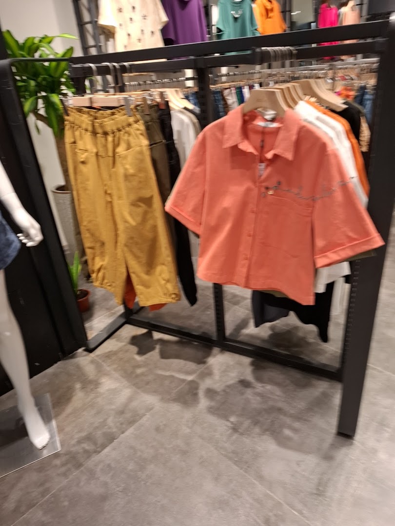 Clothing racks with various garments and a mannequin inside a shop.
