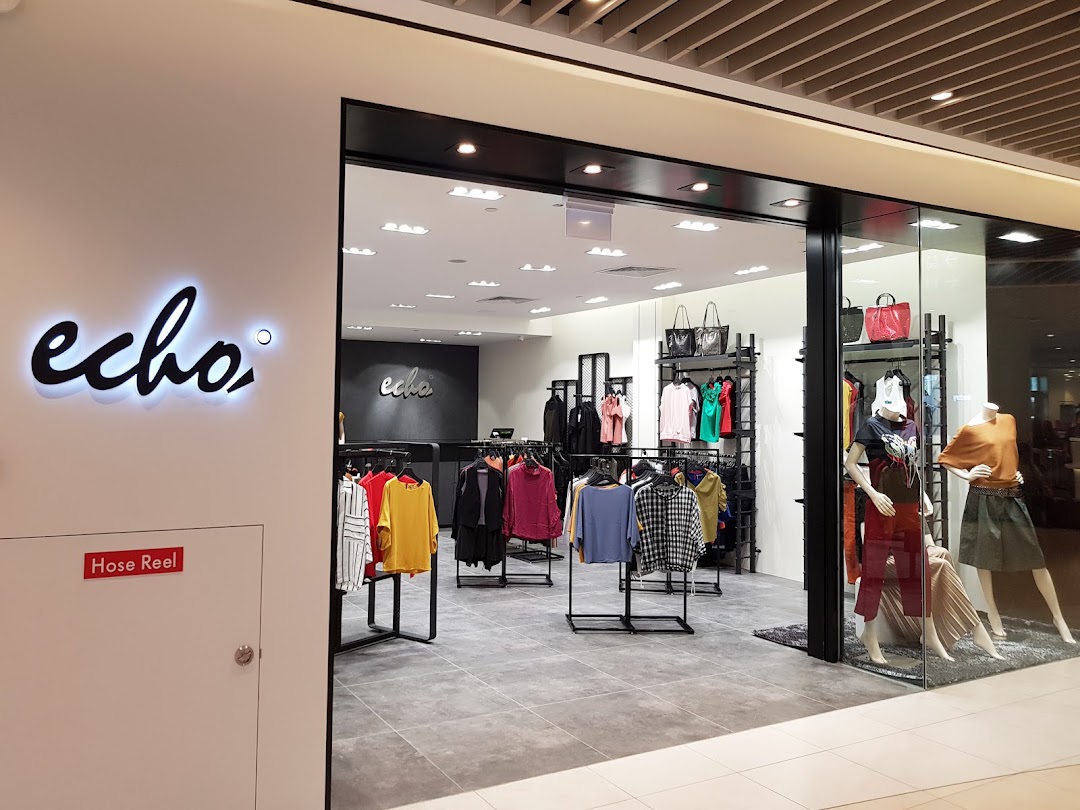 Entrance of a clothing store with mannequins and clothes racks visible inside.