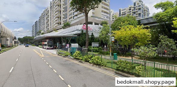 Exterior view of Bedok Mall entrance with a bus stop and street.