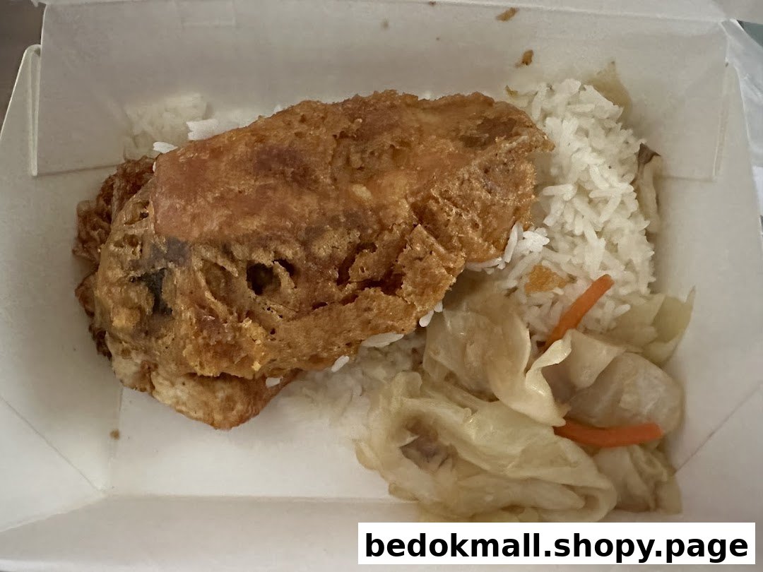 A takeaway meal with fried chicken/omelet, rice, and vegetables in a box.