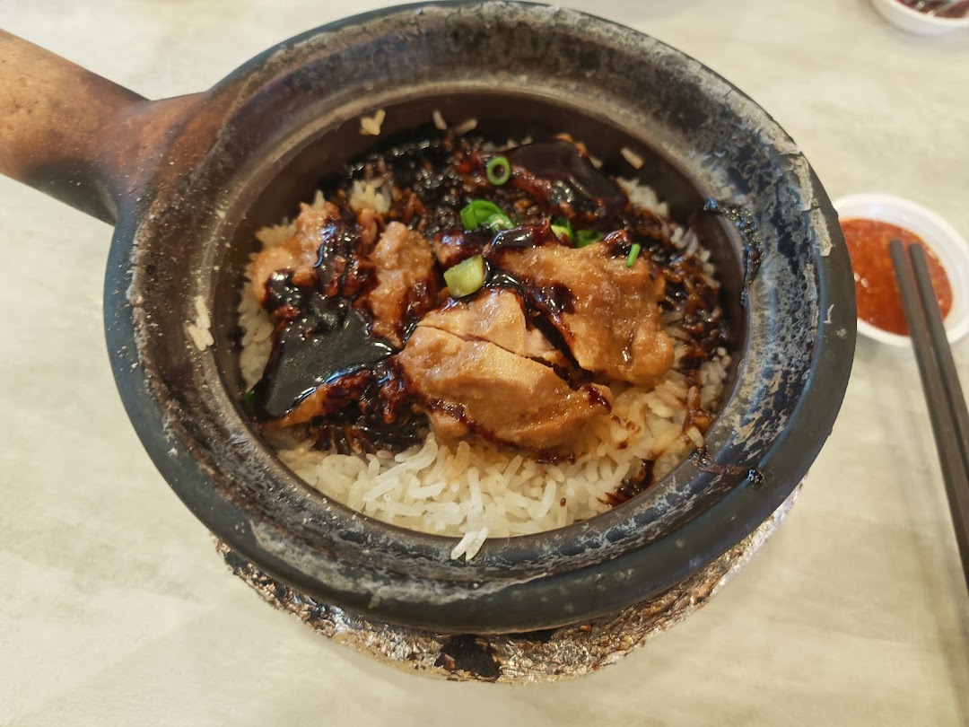 Close-up of claypot rice with chicken and sauce, served with chili.