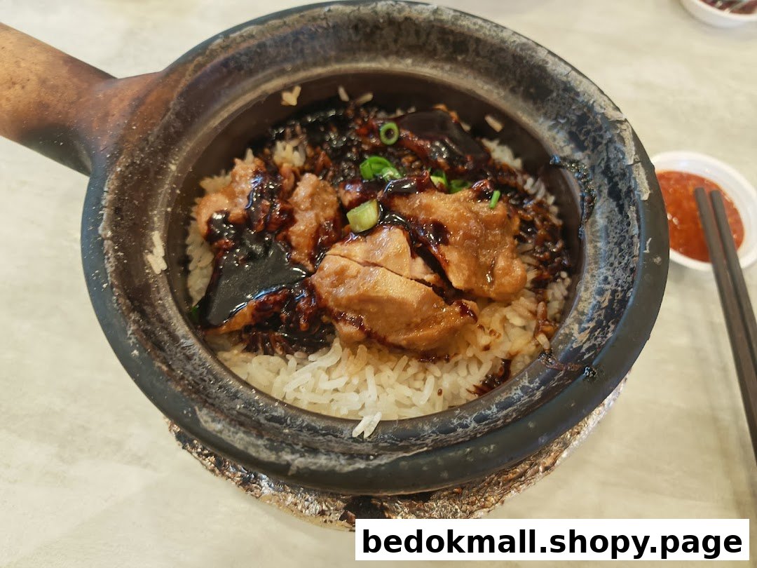 Close-up of claypot rice with chicken and sauce, served with chili.