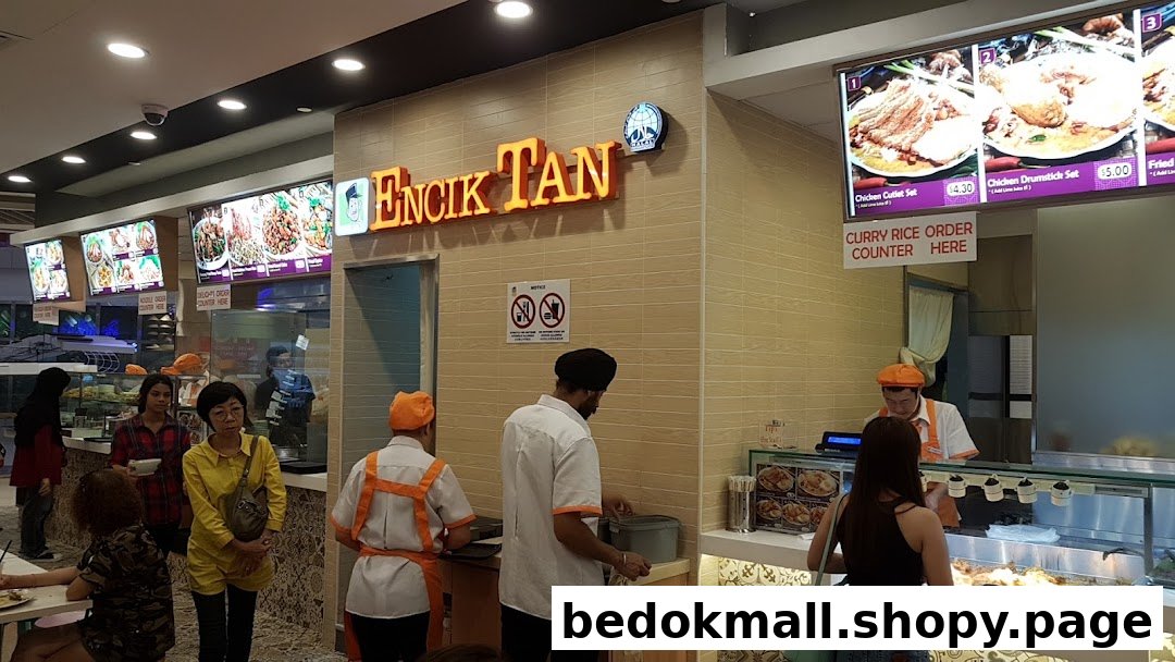 Interior view of Encik Tan food counter with staff, customers, and menu boards.