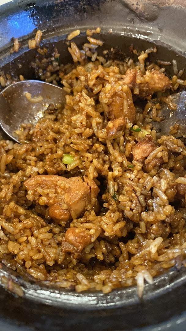 Claypot chicken rice with a spoon in a dark bowl.