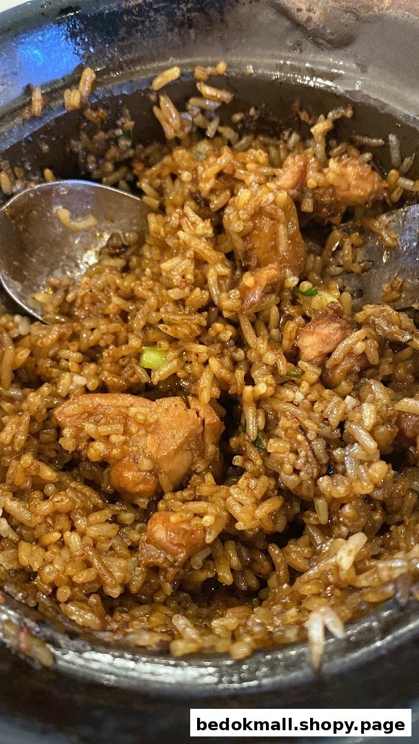 Claypot chicken rice with a spoon in a dark bowl.