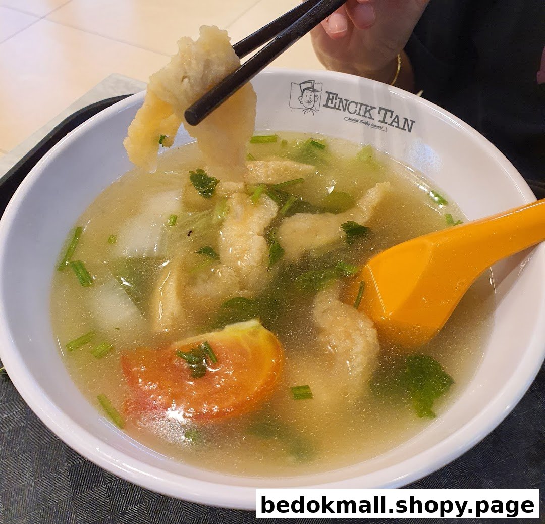 A bowl of soup with food being picked up by chopsticks.