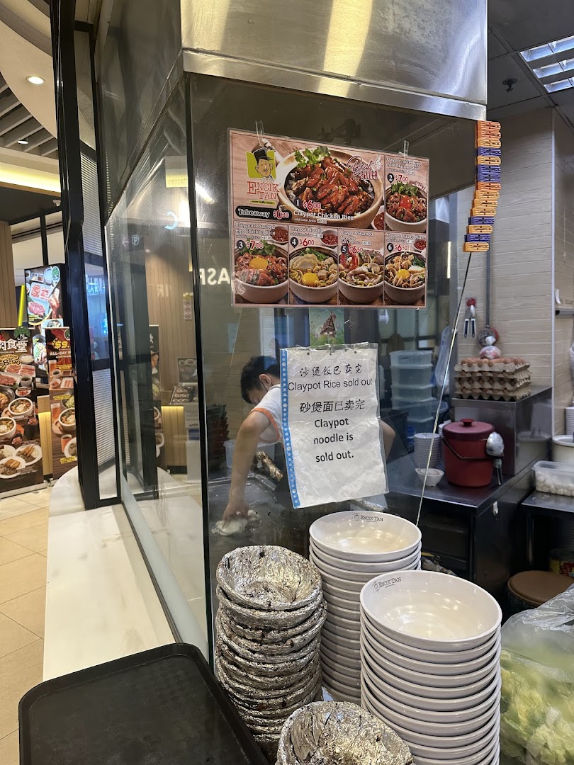 Interior view of a food stall with a worker, menu, and stacked bowls.