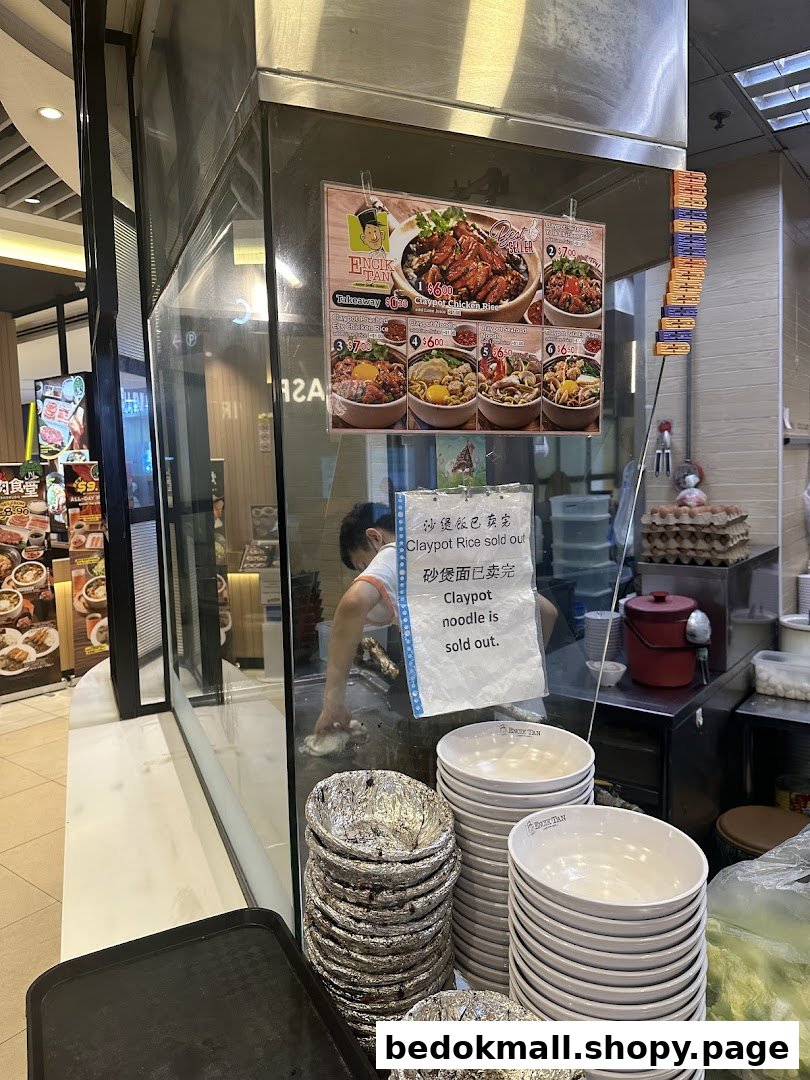 Interior view of a food stall with a worker, menu, and stacked bowls.