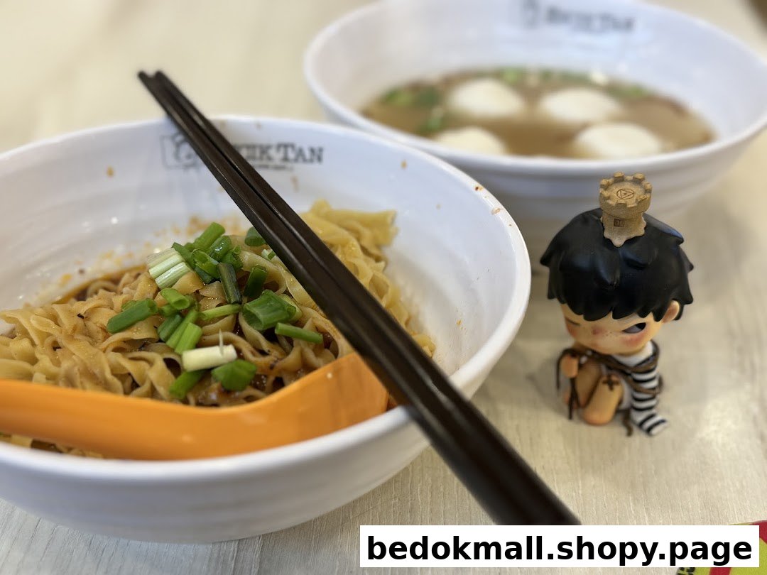 Two bowls of noodles and soup with a small figurine on a table.