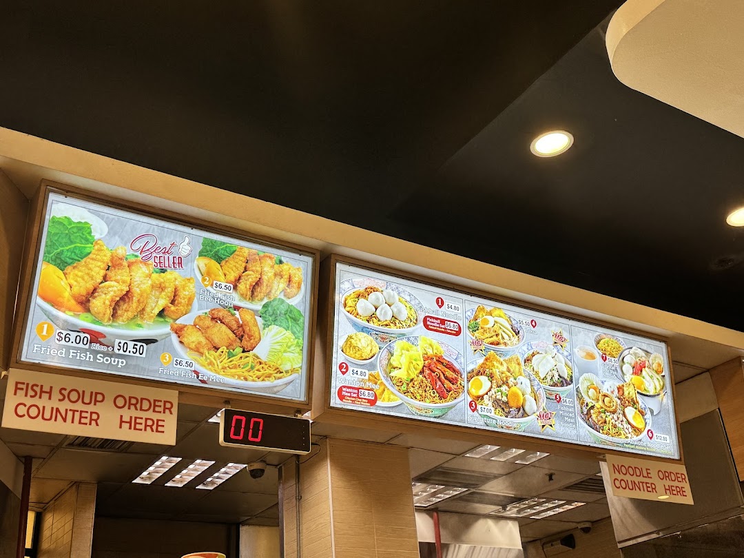 Illuminated menu boards display various food items and prices above order counters.