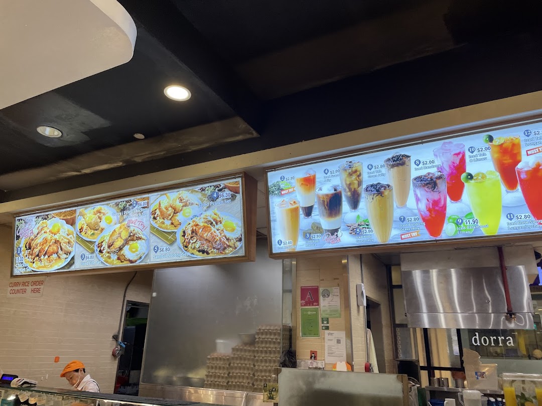 Illuminated menu boards display food and drinks above a shop counter.