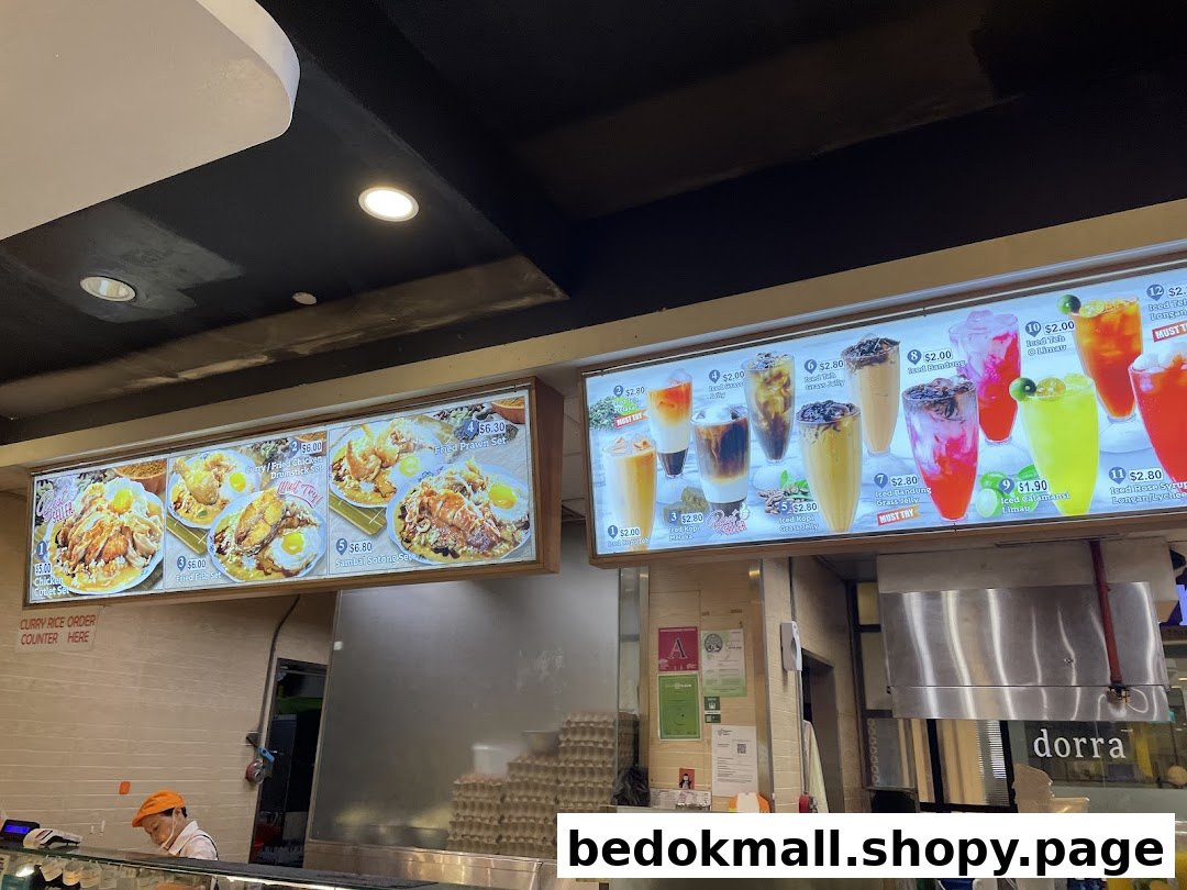 Illuminated menu boards display food and drinks above a shop counter.