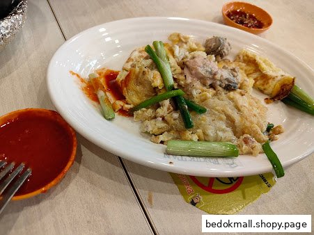 A plate of fried oyster omelette with sauces on a table.