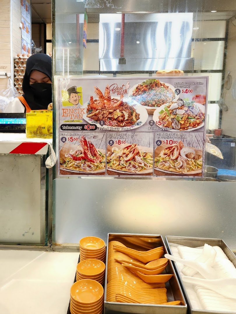 Food stall counter with large menu display and utensils.