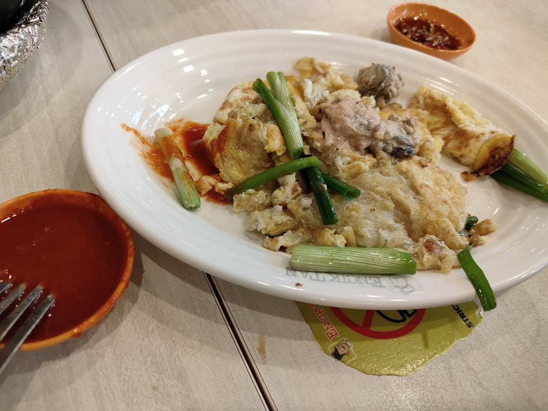 A plate of oyster omelette with spring onions and two bowls of sauce.