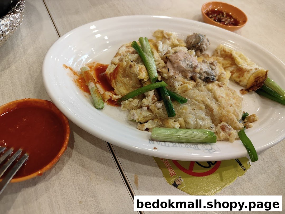 A plate of oyster omelette with spring onions and two bowls of sauce.