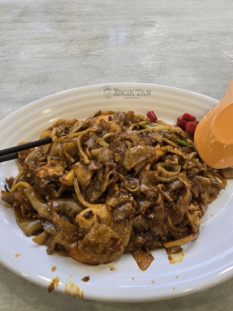 A plate of stir-fried noodles with chopsticks and a spoon.