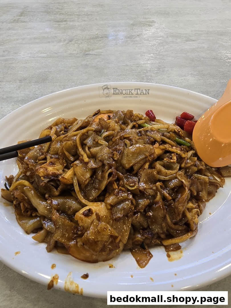 A plate of stir-fried noodles with chopsticks and a spoon.
