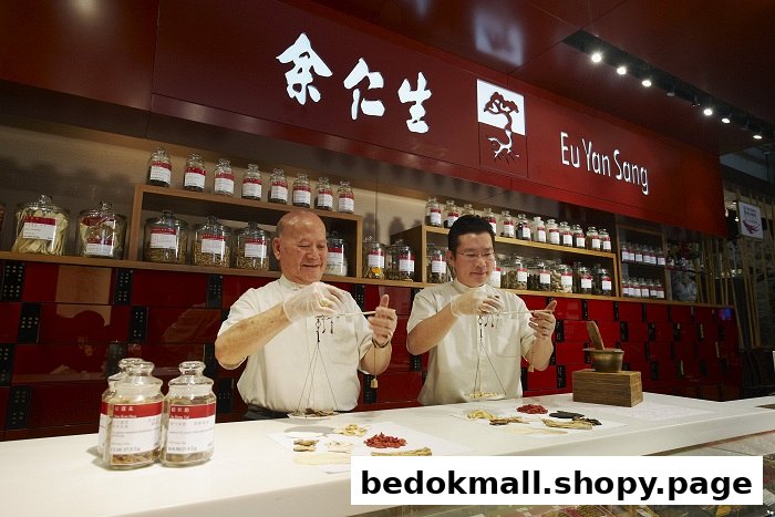 Two staff members are preparing traditional Chinese medicine ingredients behind a counter.