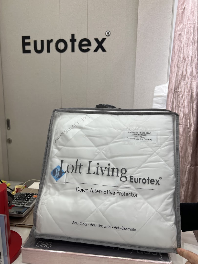 Packaged mattress protector displayed in a Eurotex shop interior.