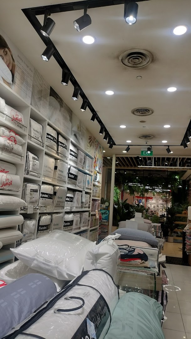 Interior view of a bedding shop with shelves of packaged products and an exit sign.