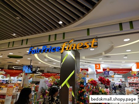 Interior view of FairPrice Finest supermarket entrance with signage, products, and shoppers.